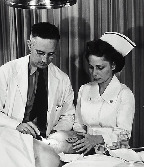 Auf diesem Bild sieht man einen Arzt und eine Pflegekraft, die einen Patienten behandeln.
